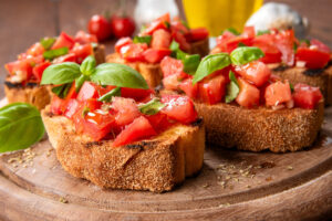 Bruschetta s rajčaty, bazalkou a olivovým olejem se podává na opečeném pečivu.