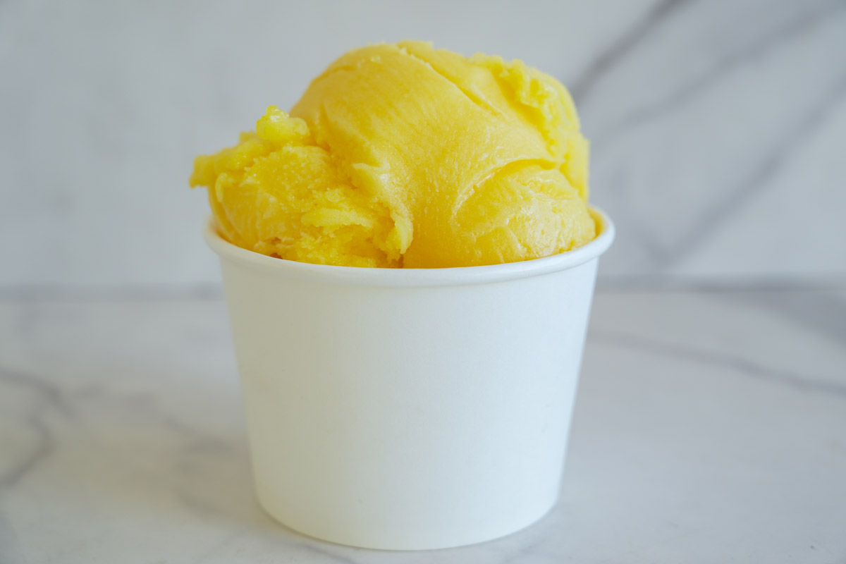 Mangový sorbet podávaný v malém kelímku příjemně osvěží během letních veder.