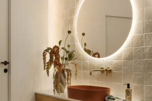 Moderní koupelna s podsvíceným LED zrcadlem, designovým umyvadlem a minimalistickou baterií.