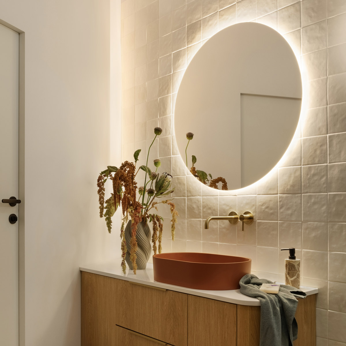 Moderní koupelna s podsvíceným LED zrcadlem, designovým umyvadlem a minimalistickou baterií.