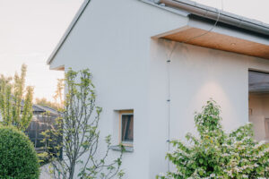 Boční pohled na dům ukazuje jednoduchou architekturu doplněnou přírodní výsadbou.