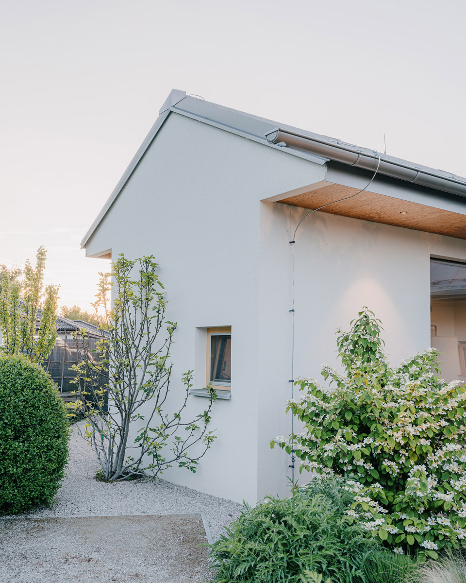 Boční pohled na dům ukazuje jednoduchou architekturu doplněnou přírodní výsadbou.
