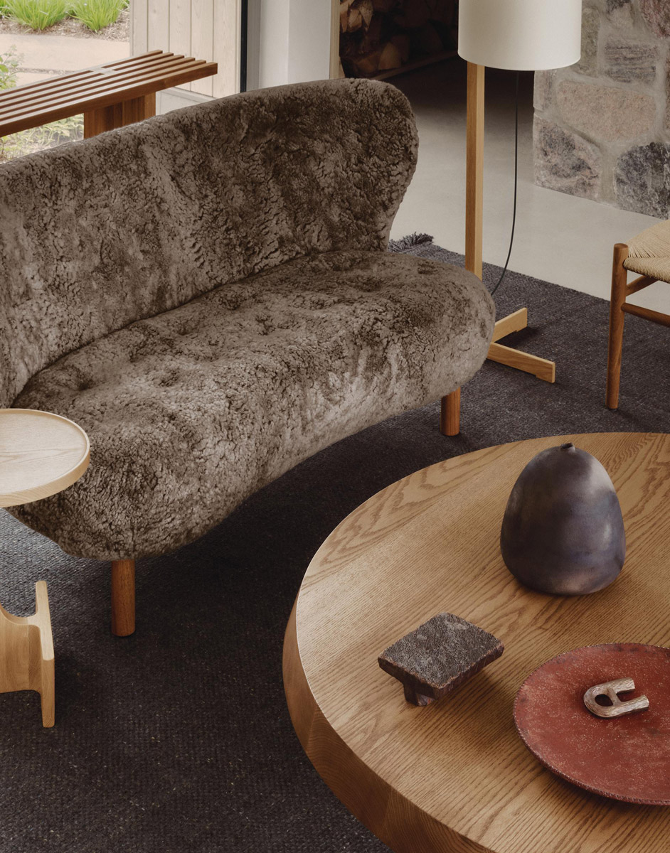 Odpočinková část s čalouněnou pohovkou, dřevěným stolkem a designovým křeslem.