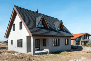 Rodinný dům po dokončení hrubé stavby s hotovou střechou a osazenými okny před finální úpravou fasády.