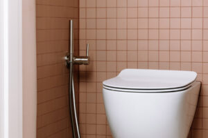 Samostatná toaleta s drobným keramickým obkladem v pudrovém odstínu a závěsným WC.