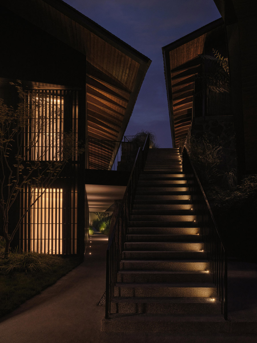 Večerně nasvícené schodiště propojuje jednotlivé budovy resortu inspirované tradiční horskou architekturou.
