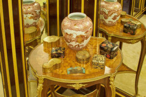 Na historickém stolku jsou vystavené japonské lakované schránky a porcelánová váza.