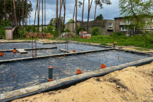 Základová deska rodinného domu připravená k betonáži s hydroizolací a prostupy inženýrských sítí.