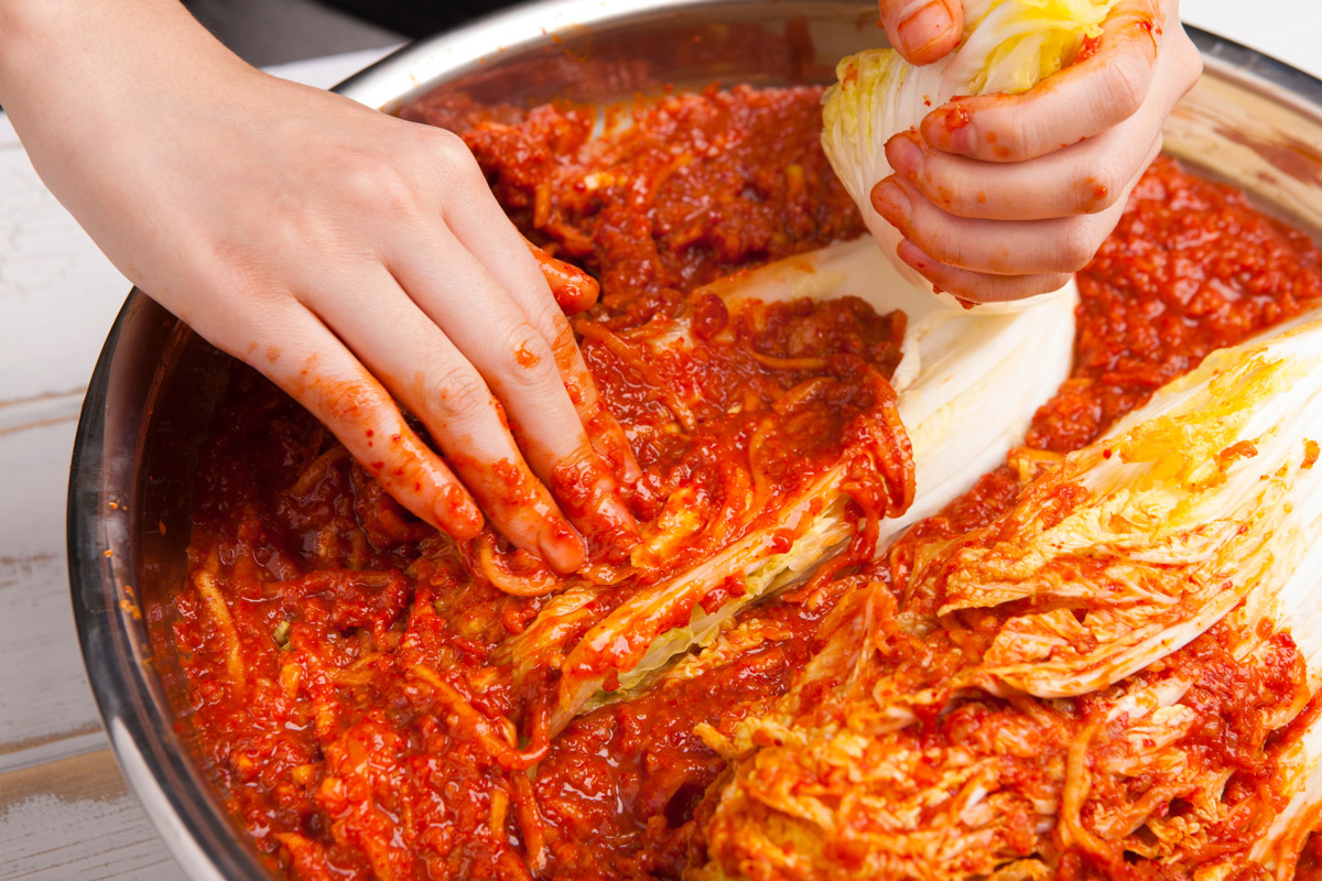 Čínské zelí se při přípravě kimchi ručně potírá pikantní chilli pastou.