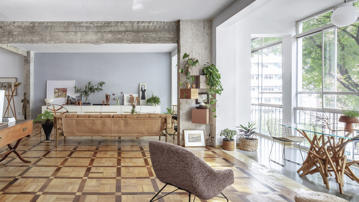 Obytná část penthousu s původní dřevěnou podlahou, přiznanou betonovou konstrukcí, designovým nábytkem a velkými okny.