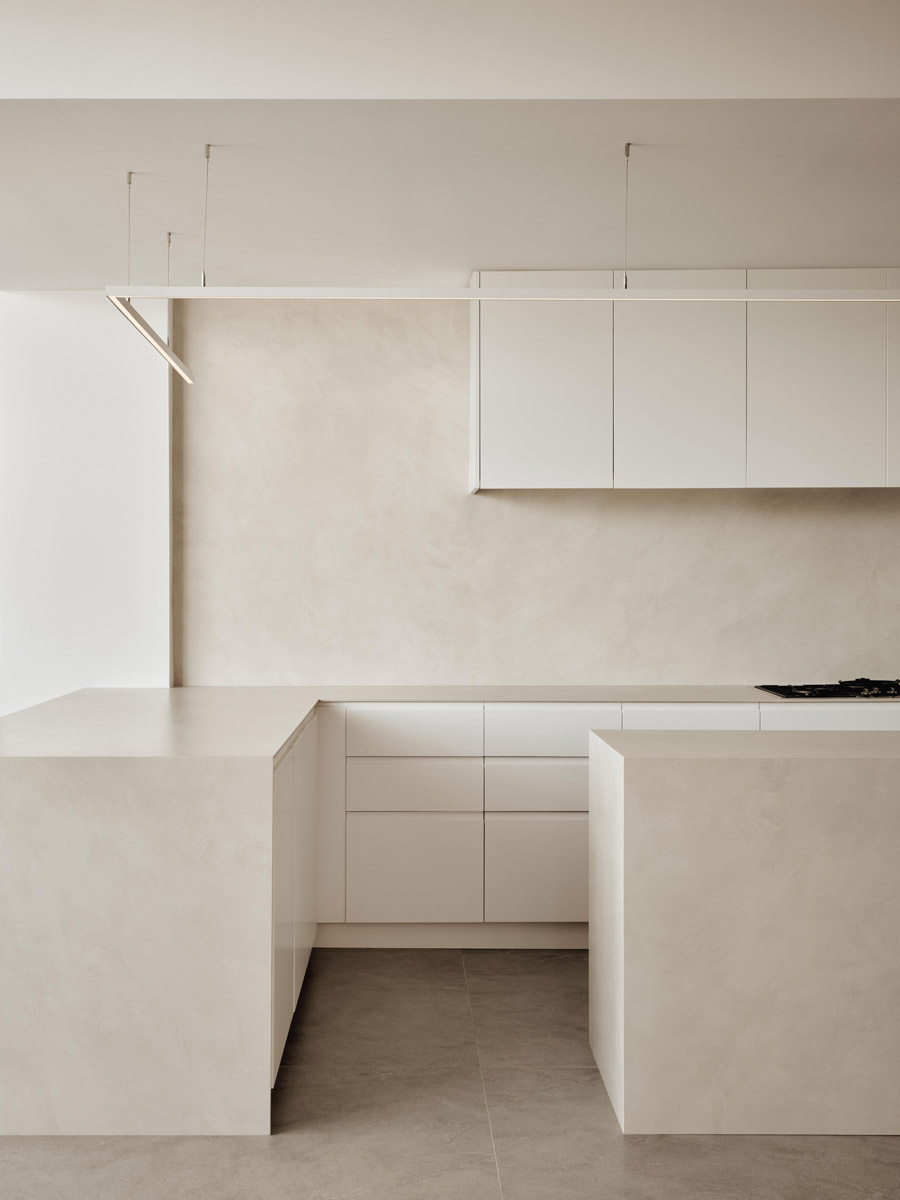 Bílá kuchyňská linka s čistými bezúchytkovými plochami vytváří klidné pozadí pro architekturu i umělecké prvky.