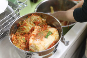 Čínské zelí obalené pikantní směsí při přípravě tradičního kimchi.