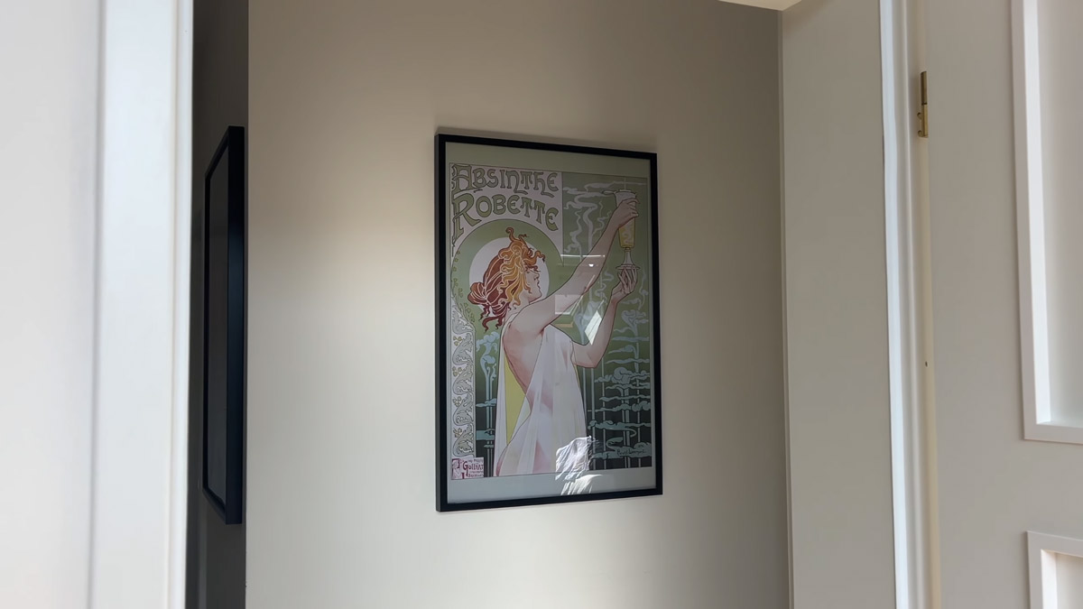 Na chodbě bytu visí plakát ve stylu secese, který oživuje jinak minimalistický interiér.