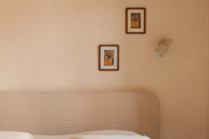 Detail ložnice ukazuje jemnou barevnost interiéru doplněnou drobnými obrazy a přírodními materiály.