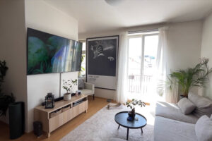 Světlý obývací pokoj propojený s kuchyní nabízí velkou pohovku, televizi i vstup na balkon.