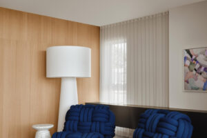 Relaxační kout tvoří dvě výrazná modrá designová křesla, vysoká stojací lampa a malý terrazzový stolek.