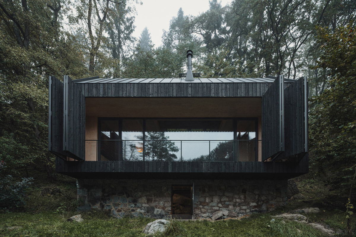 Pohled na chatu s otevřenými posuvnými okenicemi a původní kamennou podezdívkou.