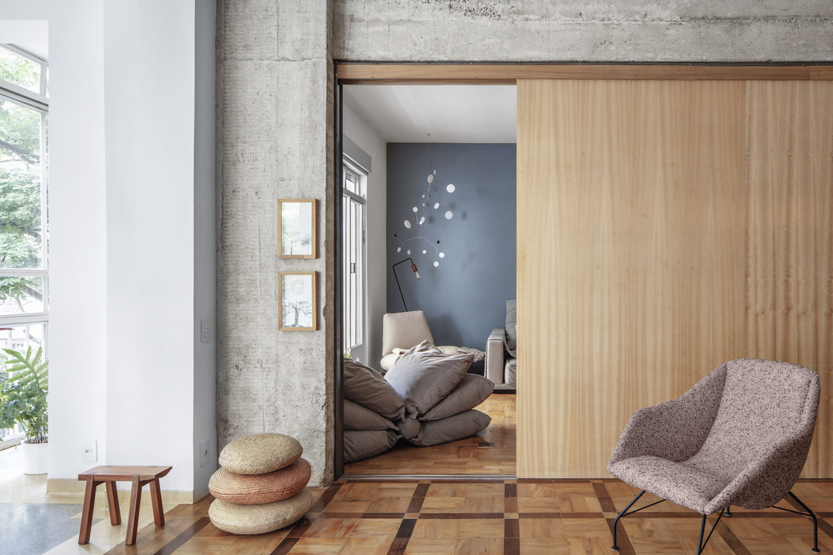 Částečně zavřená dřevěná posuvná stěna oddělující pracovnu s modrou stěnou od obytné části penthousu.