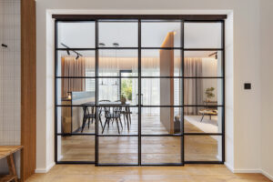 Zavřená prosklená posuvná příčka propouští denní světlo z obytné části až do vstupní haly a opticky propojuje celý apartmán.