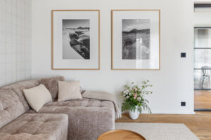 Velká pohodlná pohovka, přírodní koberec a fotografie Jizerských hor vytvářejí klidnou atmosféru horského apartmánu.