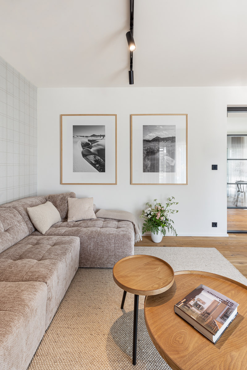 Velká pohodlná pohovka, přírodní koberec a fotografie Jizerských hor vytvářejí klidnou atmosféru horského apartmánu.