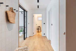 Světlá vstupní chodba s dubovou podlahou a prosklenou příčkou ukazuje, jak denní světlo prostupuje celým apartmánem.
