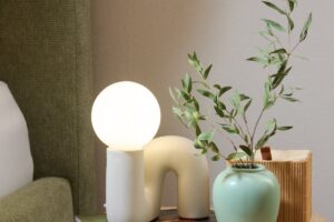 Organické tvary a keramické povrchy vnášejí do ložnice jemnou, měkkou estetiku. Stolní lampa u postele doplňuje hlavní osvětlení jako příjemný zdroj atmosférického světla.