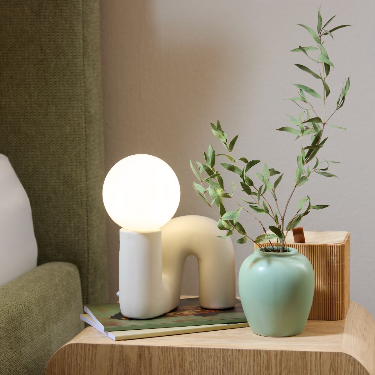 Organické tvary a keramické povrchy vnášejí do ložnice jemnou, měkkou estetiku. Stolní lampa u postele doplňuje hlavní osvětlení jako příjemný zdroj atmosférického světla.