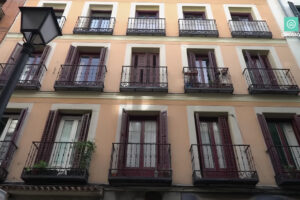 Fasáda historického madridského domu s francouzskými okny a kovovými balkony.