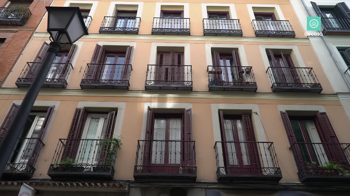 Fasáda historického madridského domu s francouzskými okny a kovovými balkony.