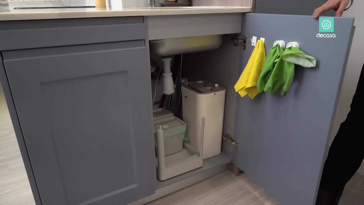 Skříňka pod kuchyňským dřezem s výsuvnými nádobami a úložným prostorem v malém bytě.
