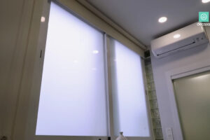 Velké matné okno, klimatizace a prosklené dveře koupelny v kuchyni madridského minibytu.