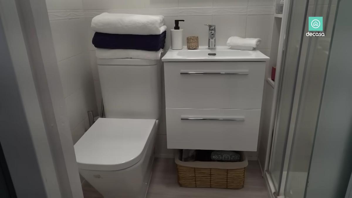Úzká koupelna s toaletou, závěsnou umyvadlovou skříňkou a sprchovým koutem.