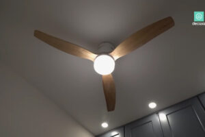 Stropní ventilátor s dřevěnými lopatkami a integrovaným světlem v madridském minibytě.