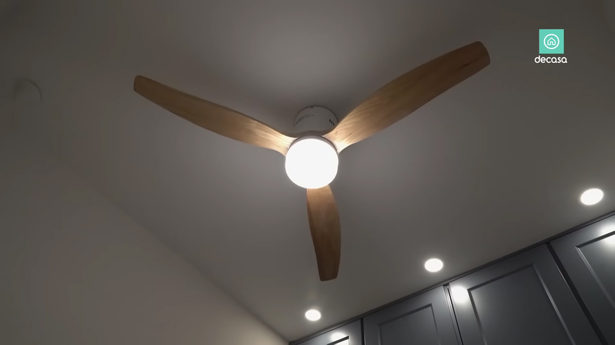 Stropní ventilátor s dřevěnými lopatkami a integrovaným světlem v madridském minibytě.