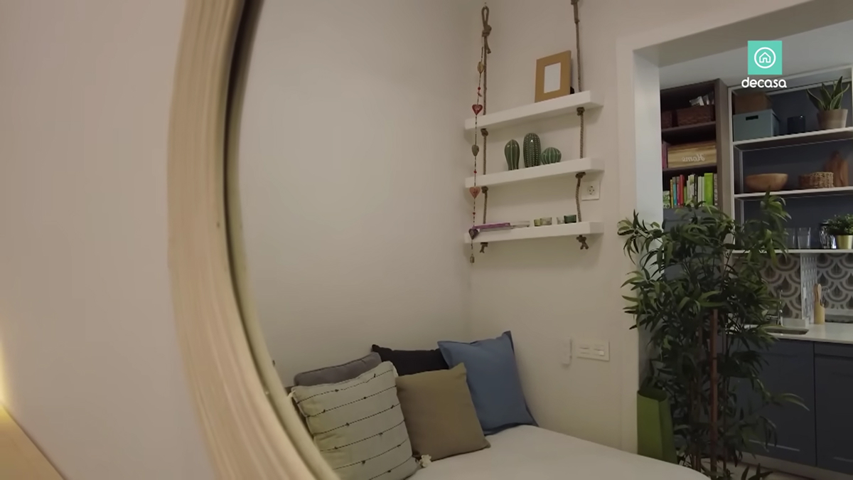 Kulaté zrcadlo odrážející ložnici a kuchyň madridského minibytu.