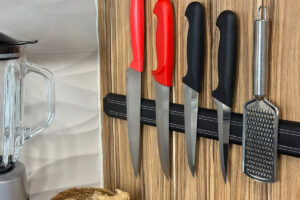 Kuchyňské nože zavěšené na magnetické liště na stěně.