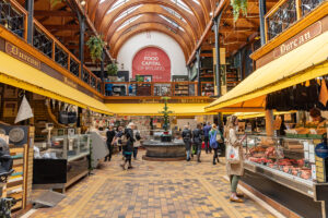 Interiér historické tržnice English Market v irském Corku s prodejními stánky a návštěvníky.