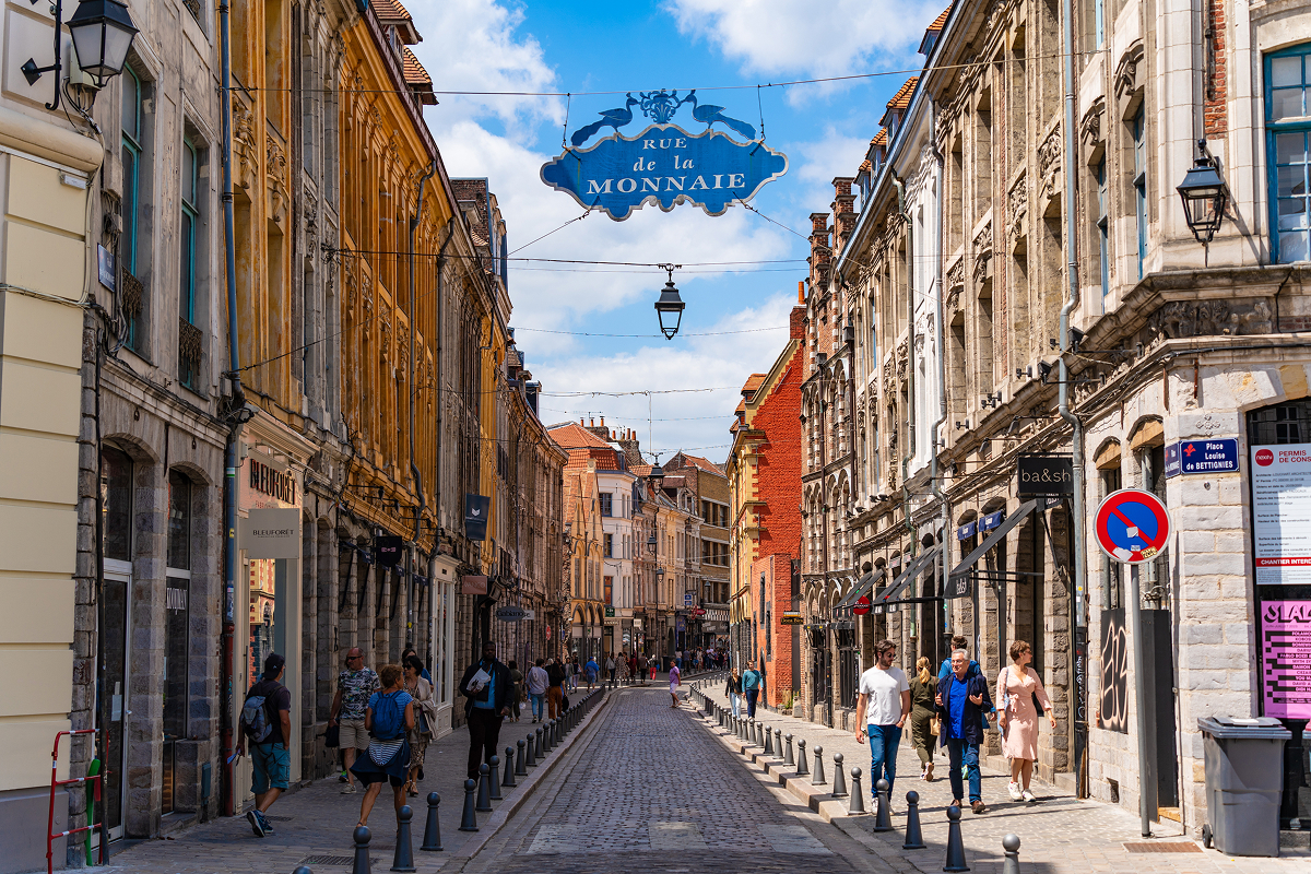 Historická ulice Rue de la Monnaie s dlážděnou vozovkou a starými domy ve francouzském Lille.