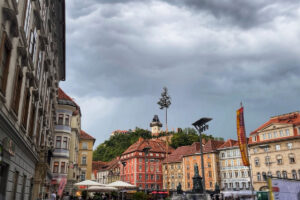 Historické centrum Štýrského Hradce s barevnými domy a hodinovou věží na vrchu Schlossberg.
