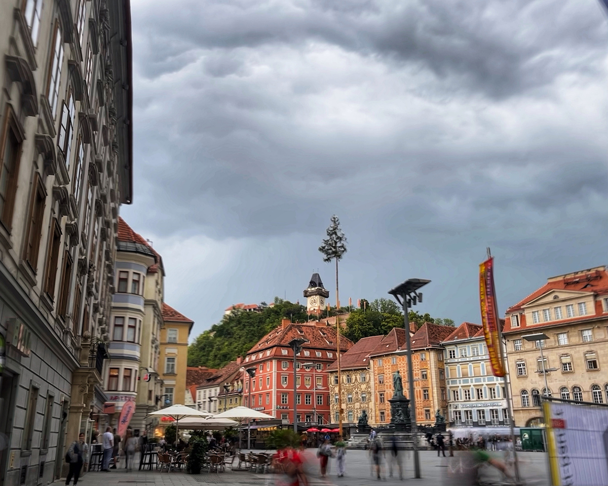 Historické centrum Štýrského Hradce s barevnými domy a hodinovou věží na vrchu Schlossberg.