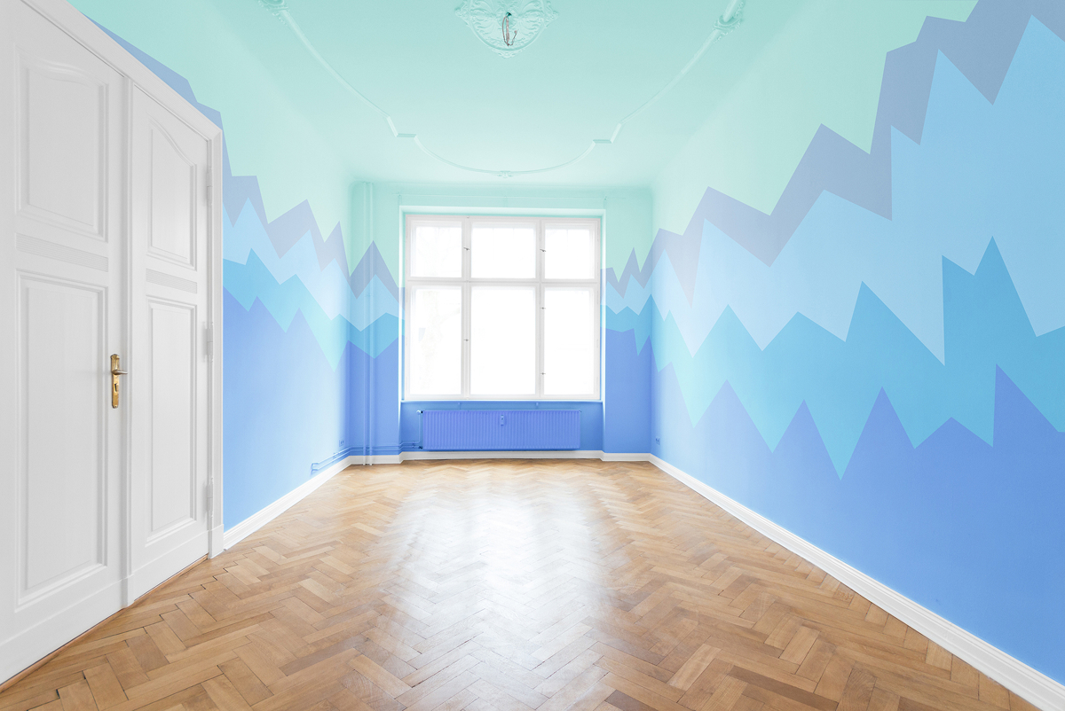Světlý dětský pokoj s modrými geometrickými vzory na stěnách, tyrkysovým stropem, bílými dveřmi a dřevěnou parketovou podlahou.