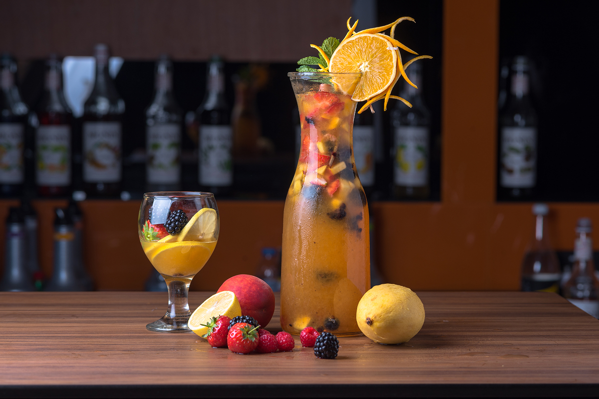 Ovocná limonáda s jahodami, ostružinami, citrusy a mátou ve skleněném džbánu a sklenici.